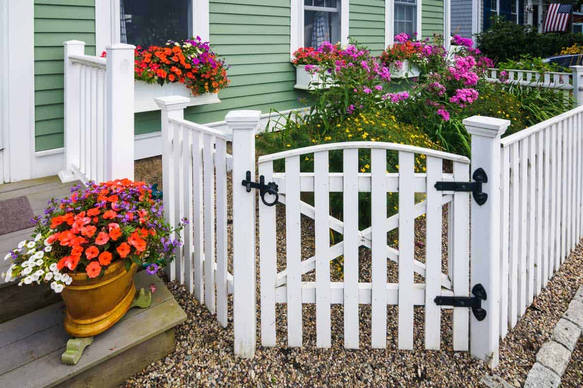 With limited space available, this home owner created an attractive pocket garden behind the gate, overflowing window boxes, and a pot of color on the steps.