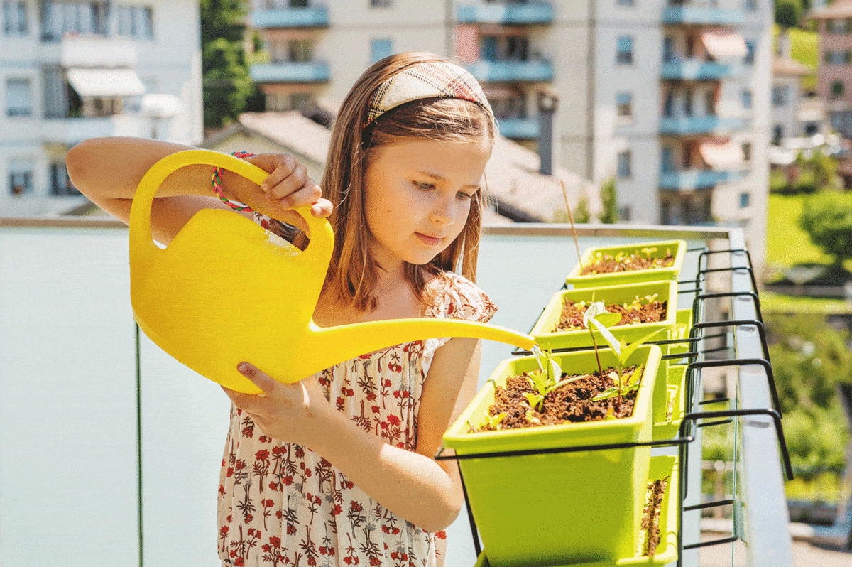 Young girl flowering plants on the balcony