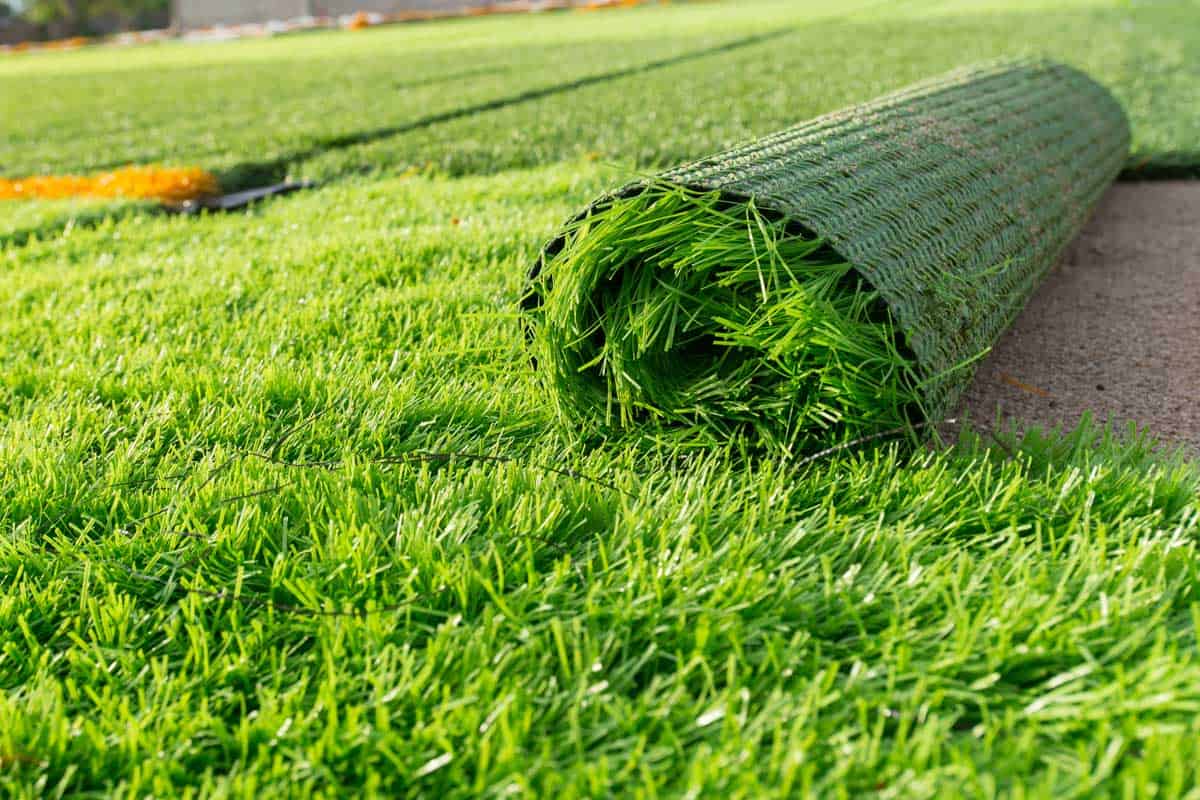 Synthetic grass lawn laying background.
