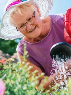 Senior woman watering flowers in the garden