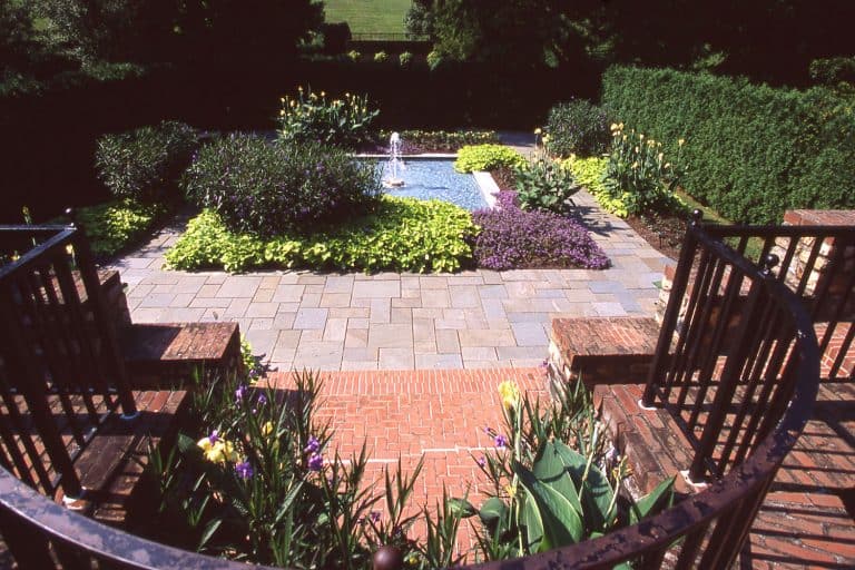 A spacious and modern garden with brick and stone flooring with a center aisle filled with flowers, 5 Of The Best Plant-Safe Concrete Cleaners