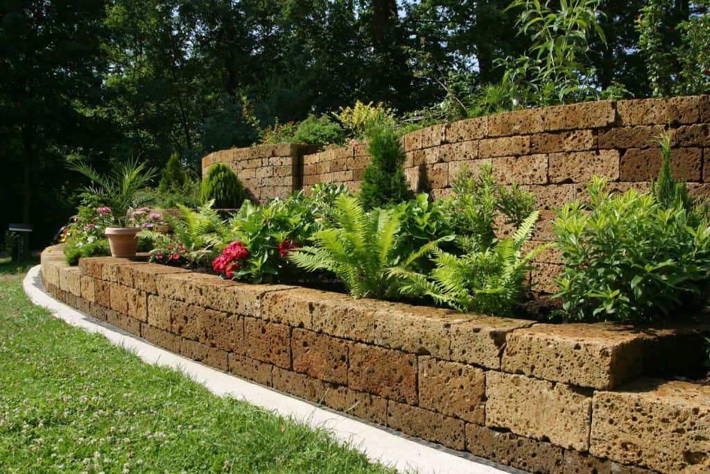 A gorgeous landscaping decorated with leaves and flowers on the retaining wall