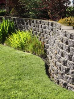 A retaining wall decorated with decorative rocks on the backyard garden