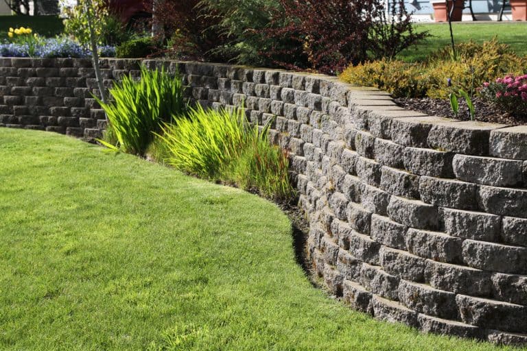 A retaining wall decorated with decorative rocks on the backyard garden