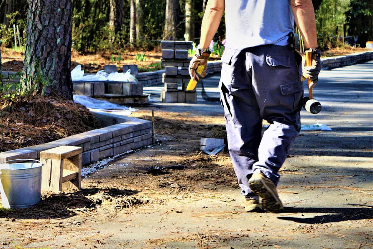 A worker carrying masonry materials for a retaining wall