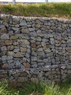 A fragment of a retaining wall made of gabions, How Tall Can A Retaining Wall Be? [Inc. Without A Permit]