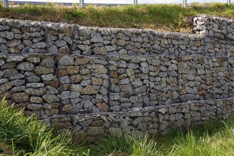 A fragment of a retaining wall made of gabions, How Tall Can A Retaining Wall Be? [Inc. Without A Permit]