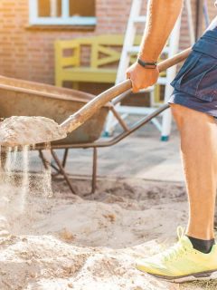 Cropped image of man digging sand with a shovel for garden, Does Sand Help With Soil Drainage?