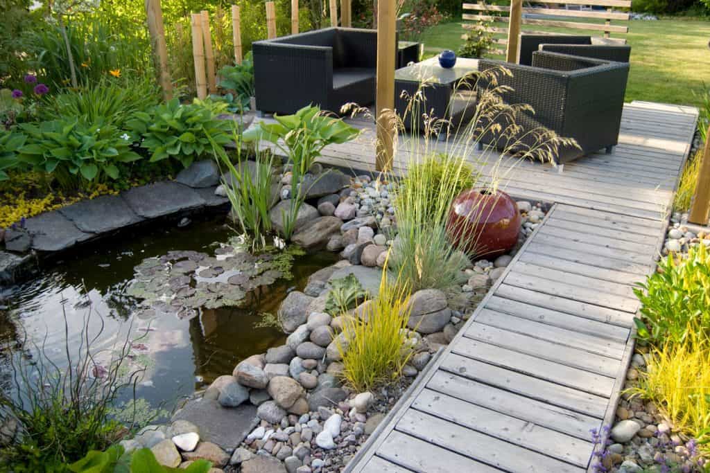 A beautiful nature themed patio with a small pond on its side