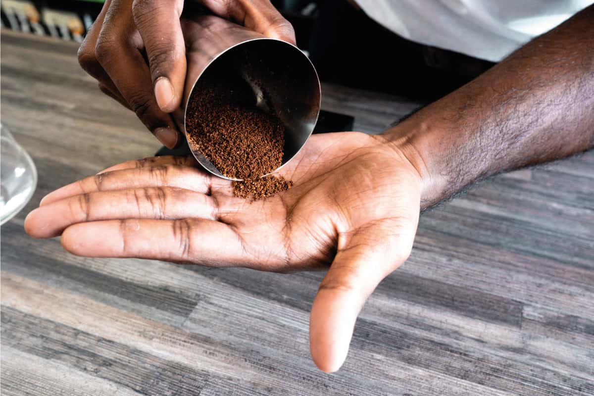 Freshly ground coffee beans being poured onto a hand