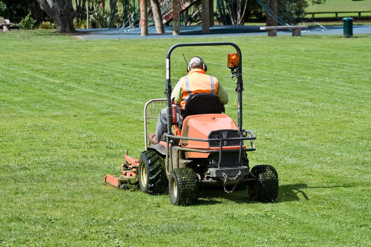 Maintenance personnel using a riding lawn mower for a golf course