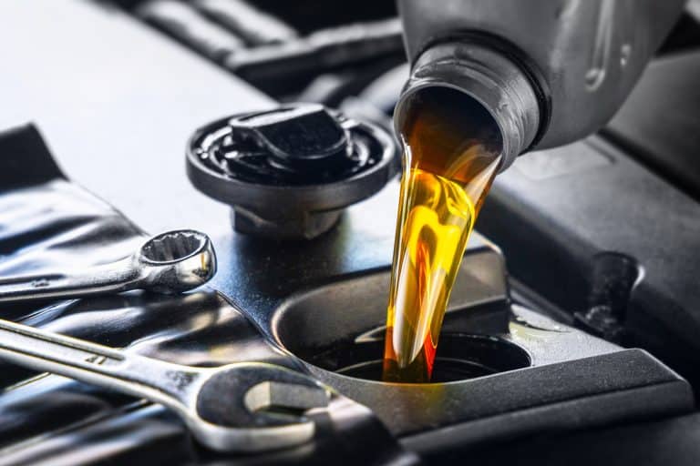Pouring motor oil for motor vehicles from a gray bottle into the engine, , oil change, auto repair shop, service - Can You Put Too Much Fuel Stabilizer In Gas