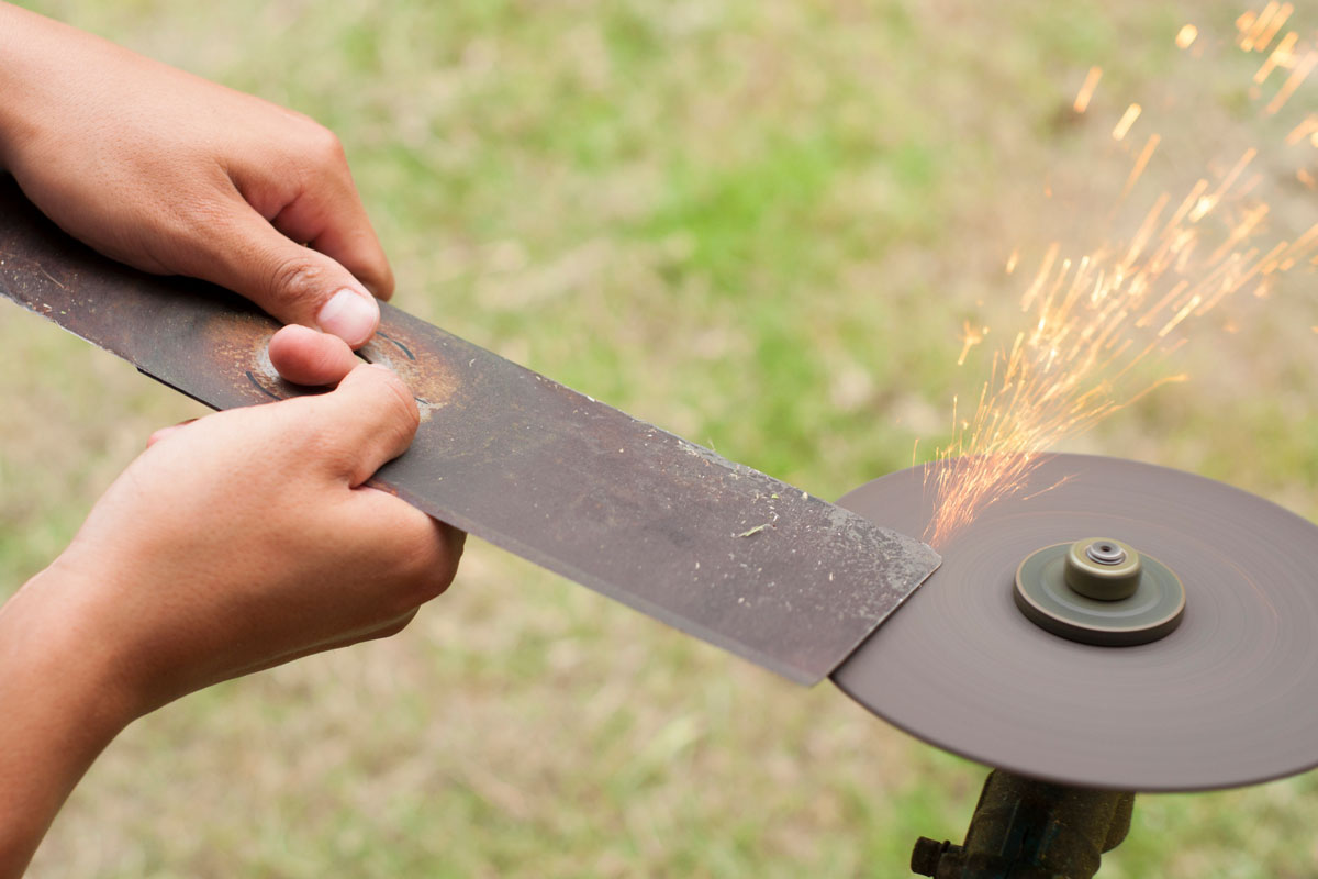 Sharpening Lawn mower blade by holding it by two hands in outdoor