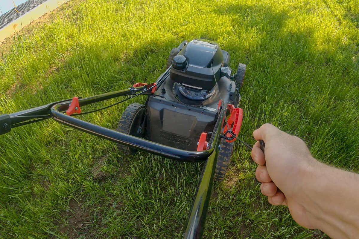 Turning on the lawn mower to lawn the front yard