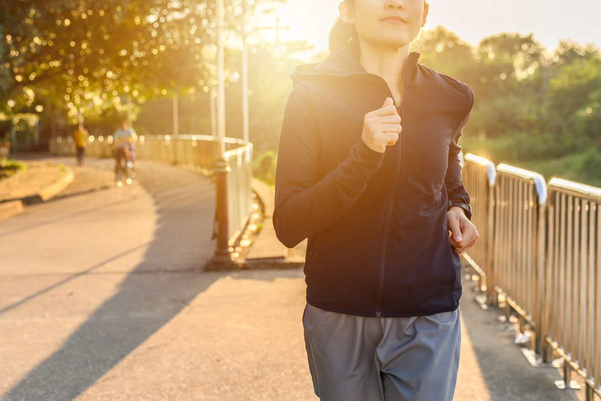 a young fit woman running in the park with sunshine warm light