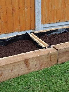 A row of raised flower planters with lining, How To Line A Planter Box [And Should You]