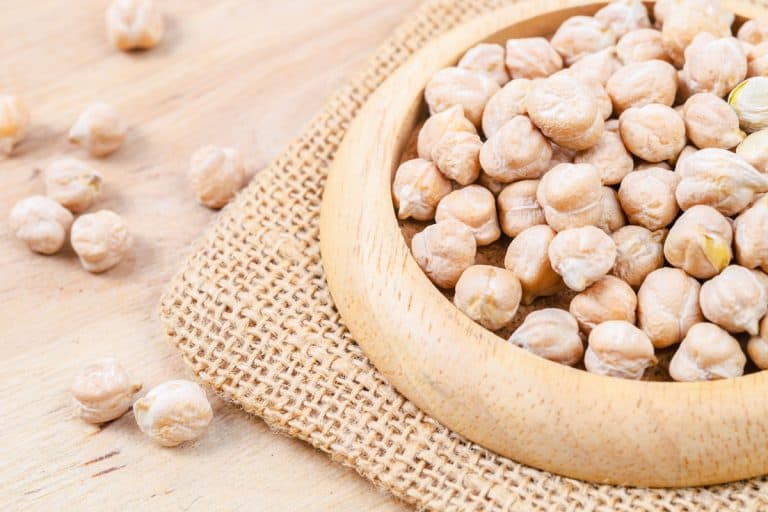 fresh uncooked chickpeas on a brown wooden bowl, close up photo, Can You Grow Beans And Chickpeas From Dried Beans? [Or Fresh!]
