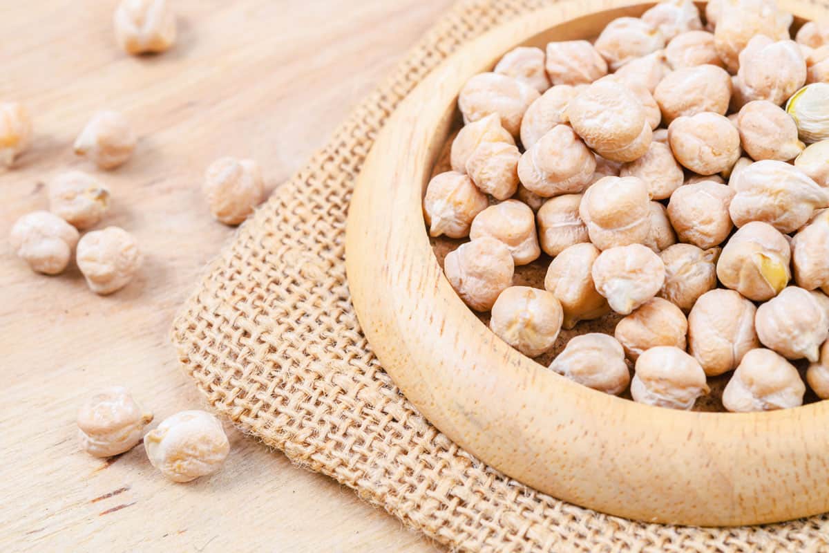 fresh uncooked chickpeas on a brown wooden bowl, close up photo