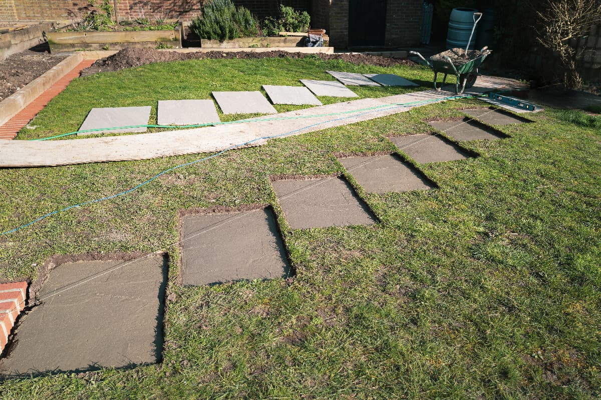 Rectangular sections cut into a lawn with concrete bases prepared for stepping stones
