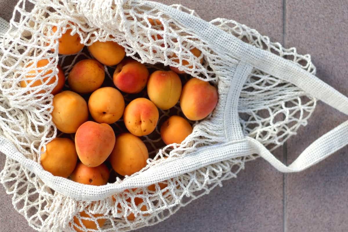 Reusable mesh bag filled with apricots. Top view.