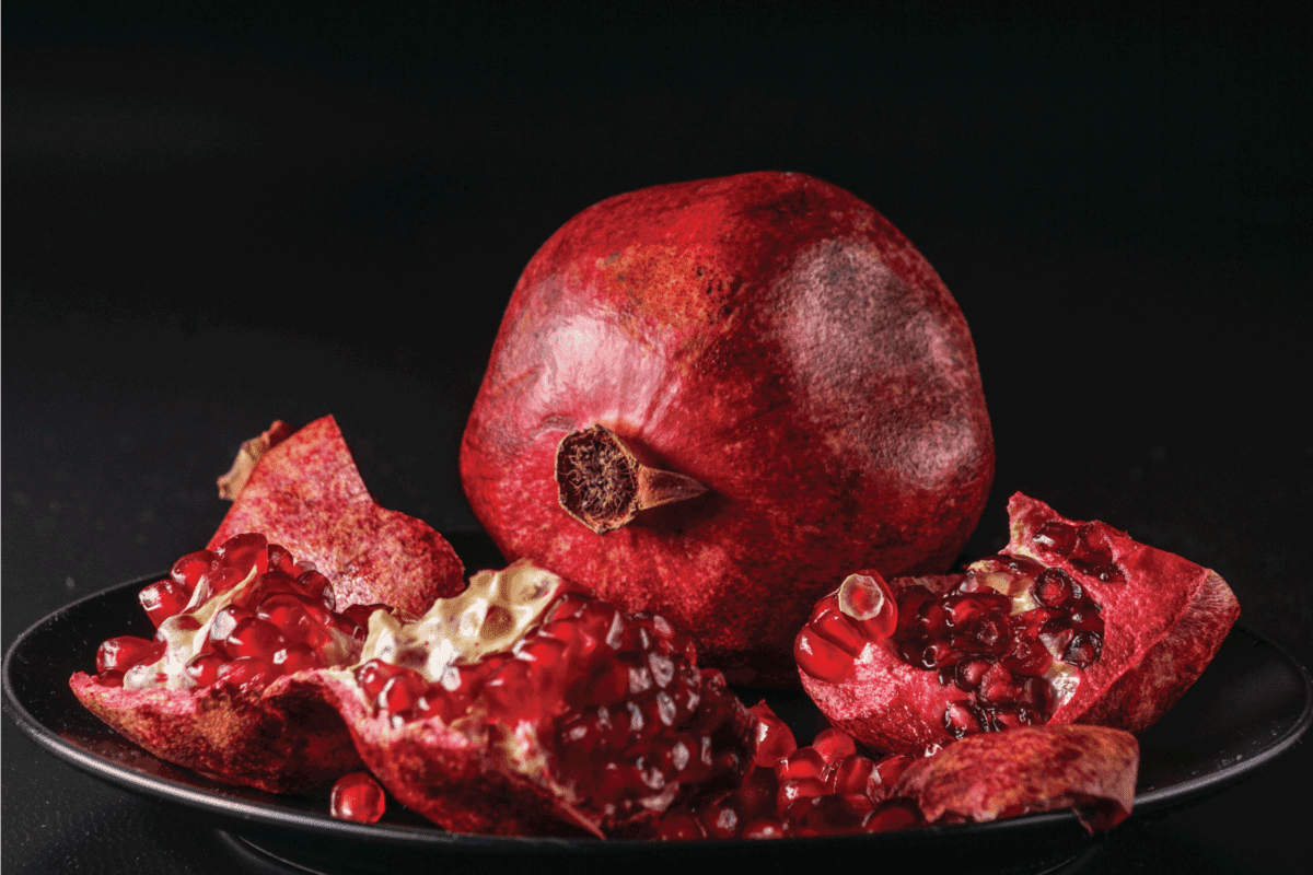 Ripe red delicious fresh pomengranate fruit, on black background