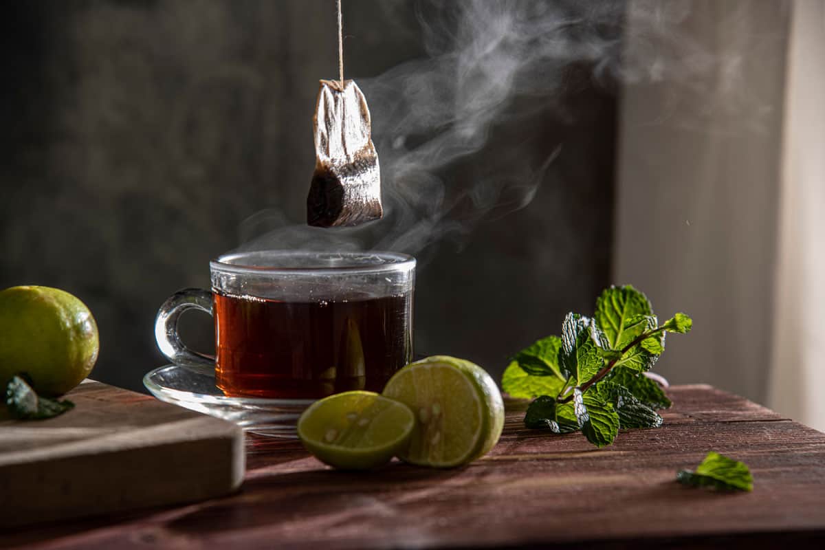 tea bag pulled from hot tea cup and a lemon beside it