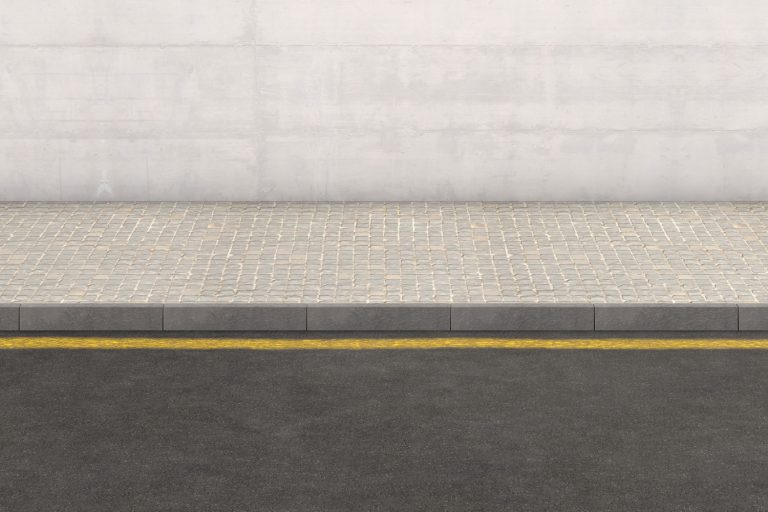 A flat front view of a section of raised sidewalk and street on a plain wall background - How To Fill Gaps Between Foundation And Sidewalk