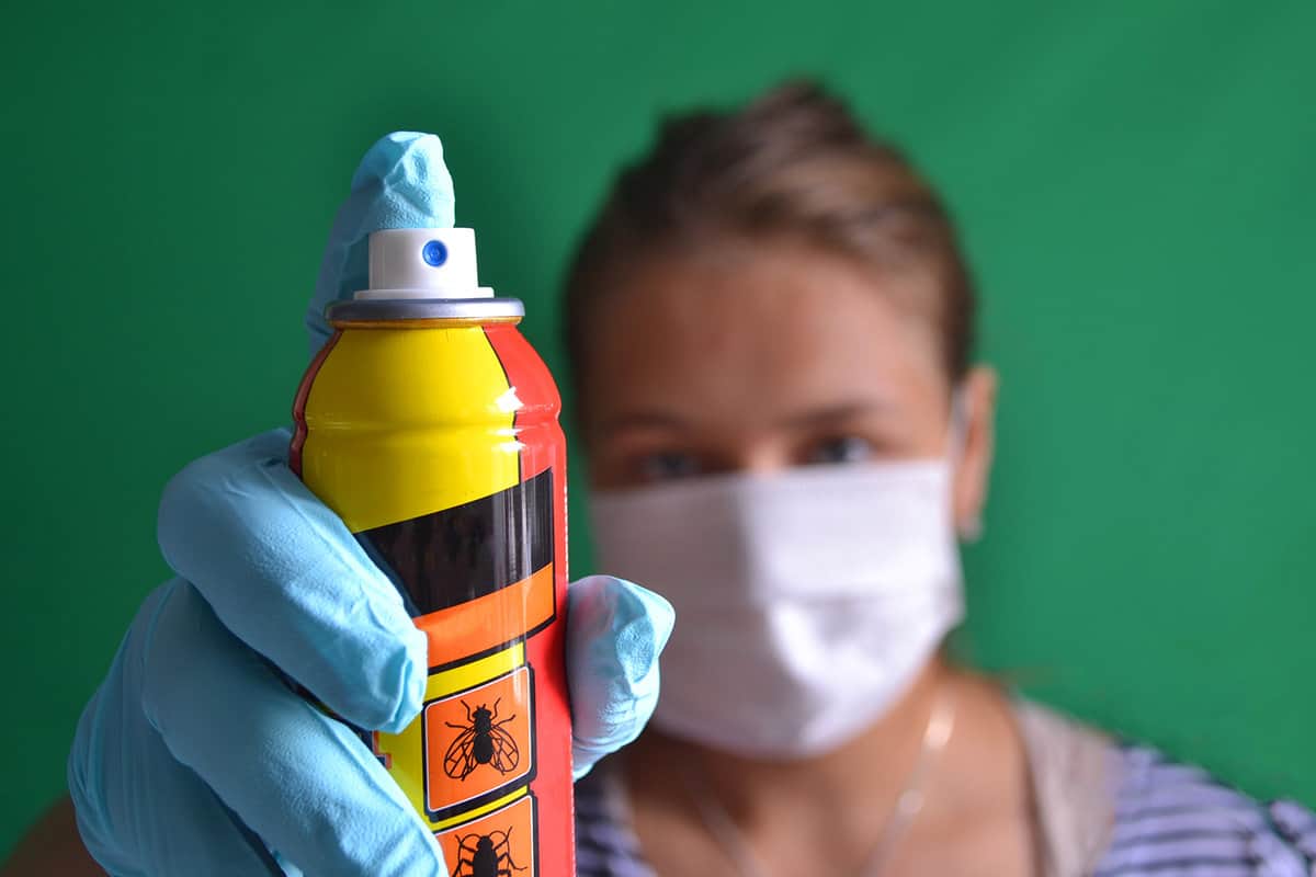 Aerosol for insect control in the hands of a woman wearing a mask