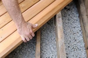 Close-up of worker putting new cedar boards on deck, How To Fill Gaps Under Gravel Board?