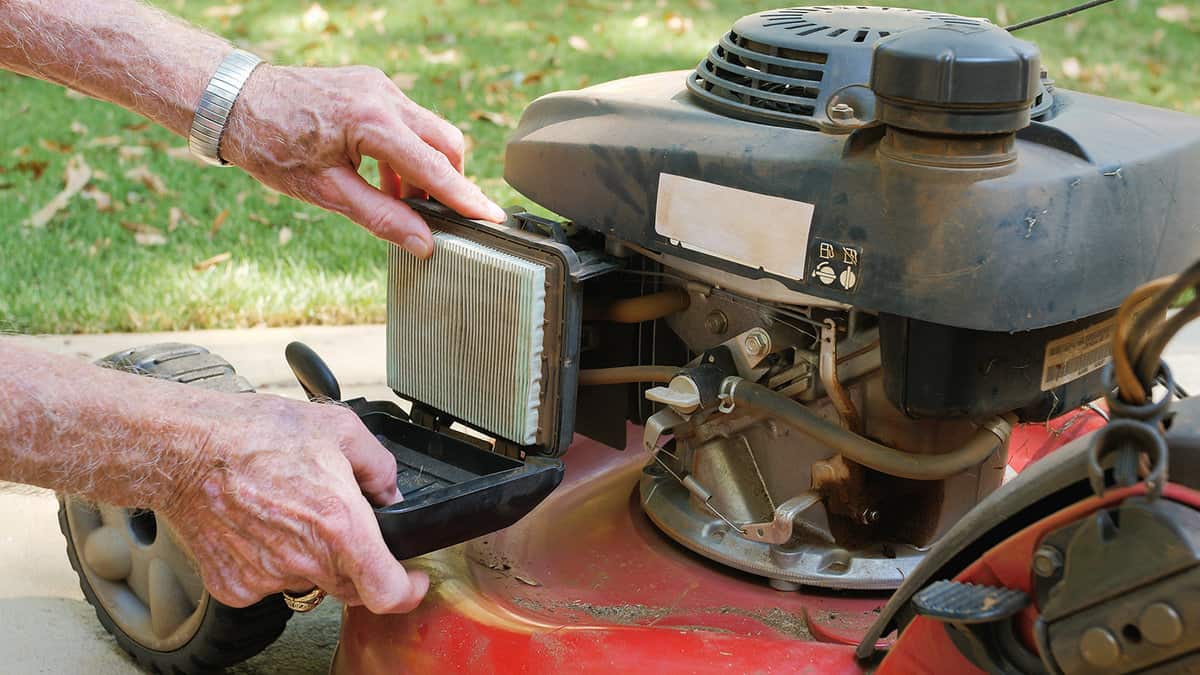 Landscaper replacing air filter on gas powered lawn mower