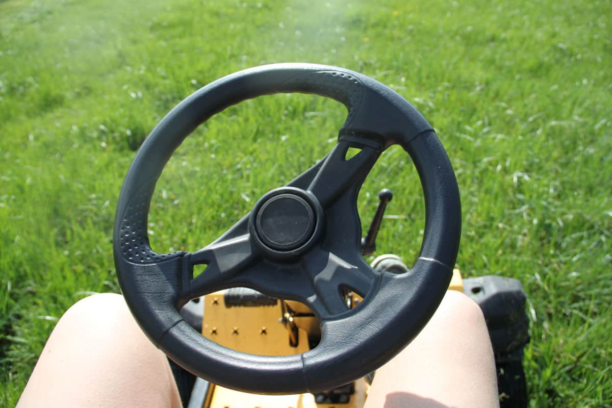 Steering wheel of a lawn tractor cutting grass
