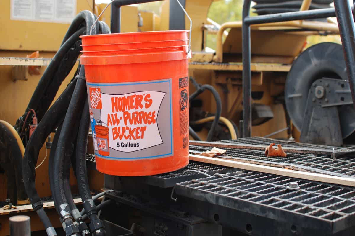 A Home Depot brand all-purpose 5 gallon bucket sitting on a construction equipment vehicle
