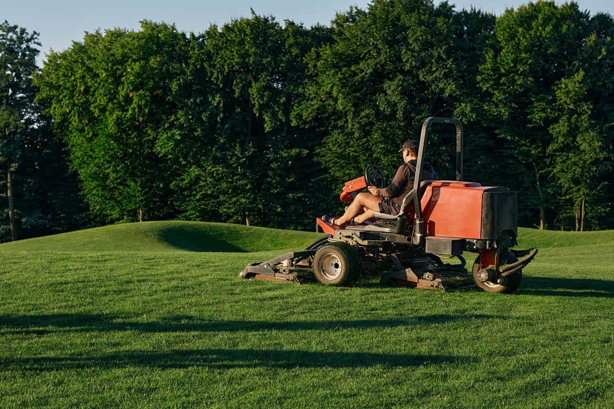Greenkeeper. Golf course maintenance worker, cutting green grass