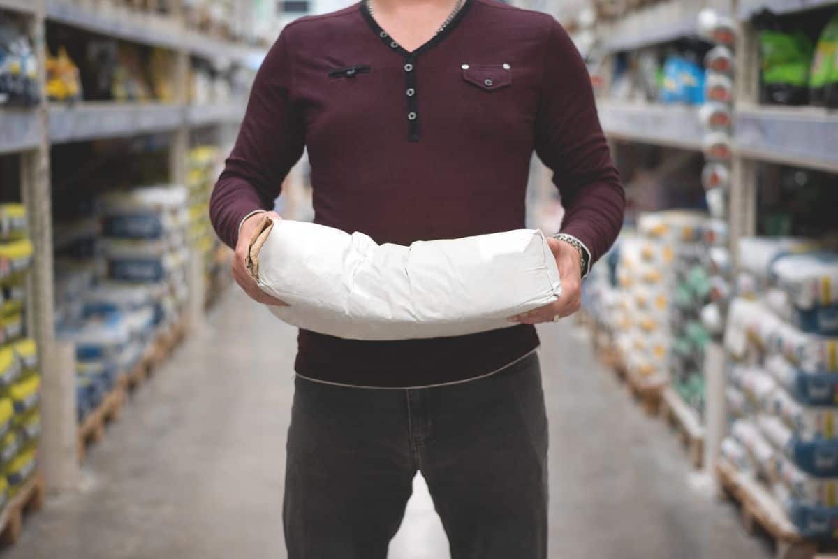 A builder is holding in hand a bag of plaster or putty in a construction store.