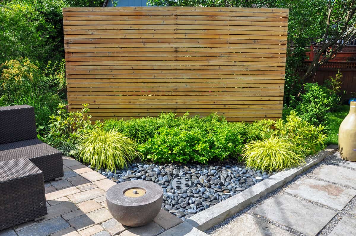 Beach pebbles, square cut flagstone and brick landscape pavers and simple plantings provide ample texture and contrast in small contemporary backyard