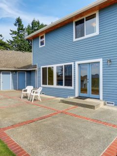 Blue house backyard with concrete floor patio area and well kept garden. - How Many Wheelbarrows Are In A Yard Of Concrete?