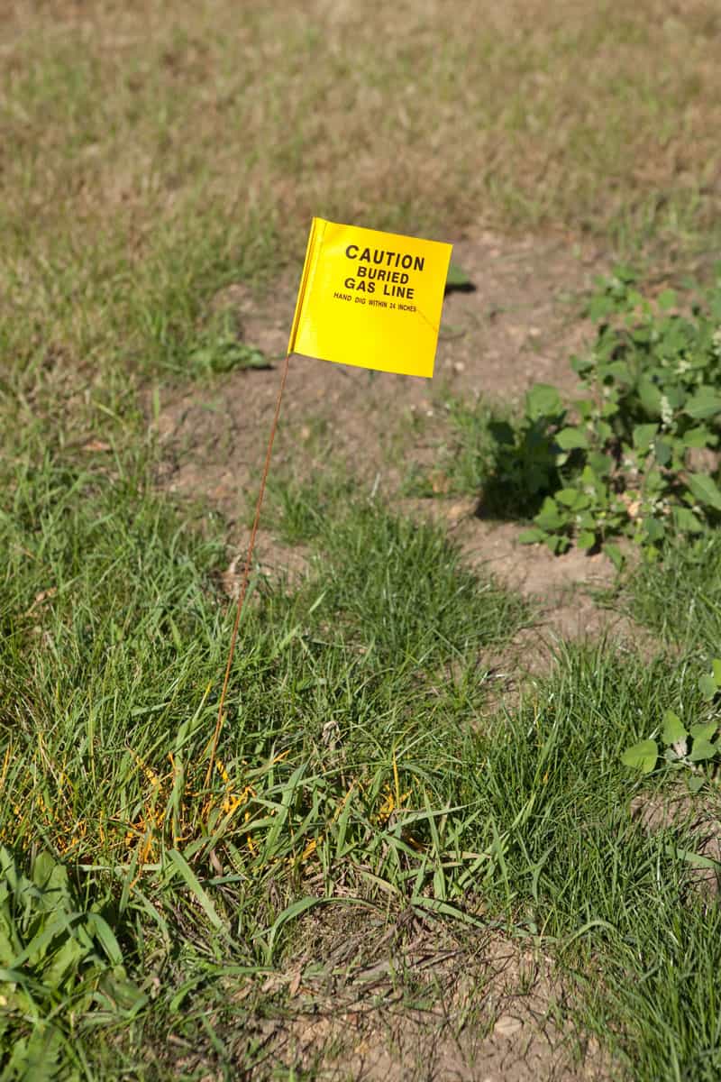 Caution Buried Gas Line Flag and Yellow Stripe on Grass