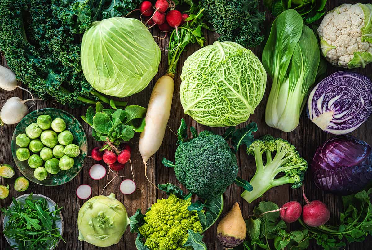 Crucifers vegetables assortment including cabbage, broccoli, cabbage, turnip, kale, romanesco, radish, arugula, kohlrabi and swedes on wood rustic board