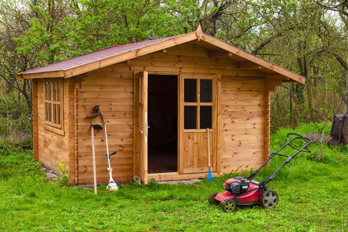Garden shed with hoe, string trimmer, rake and grass-cutter