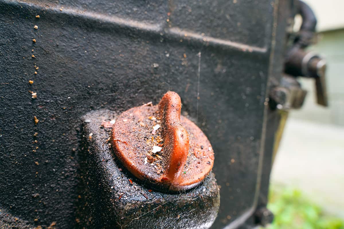 Red plastic oil dipstick cap in the body of a dirty motoblock engine of a tractor