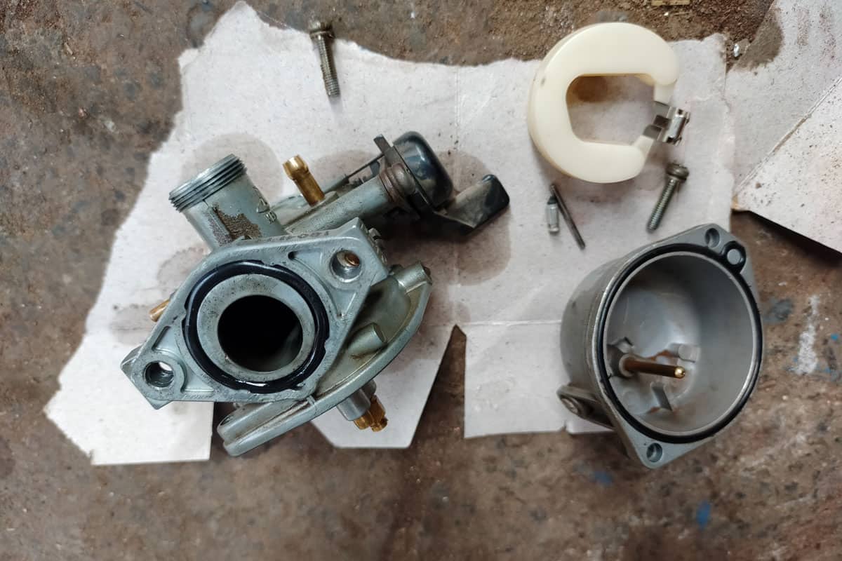 Vintage rusty engine carburetor on oily and dirty workshop floor
