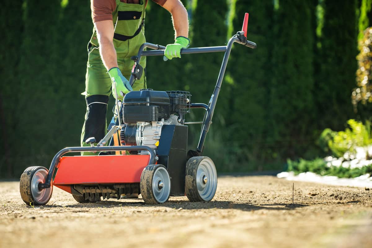 A landscaper preparing the machine harley rake for leveling and cleaning the ground