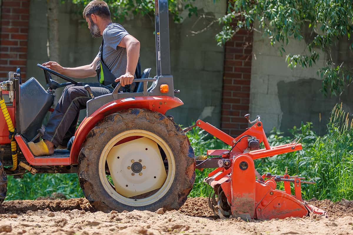 A man on a mini-excavator levels a piece of land