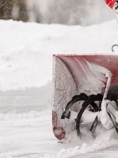A man with a red snow-covered snow blower clears the area from snow. Clearing the area from snowfall. - How To Attach Snow Blower To John Deere [Step By Step Guide]