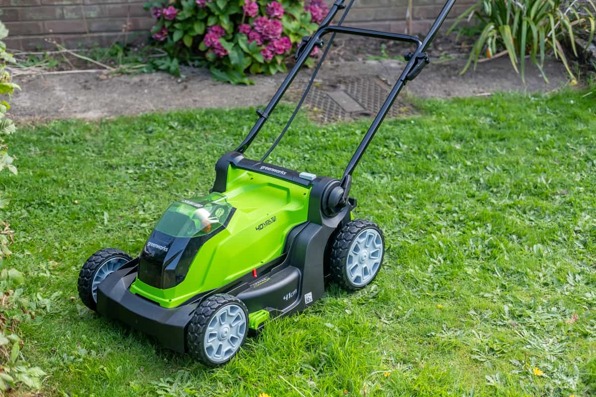 . Close up of a Greenworks 40v battery operated lawnmower used to cut the long grass of a domestic garden.