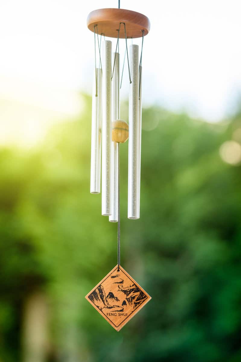 Feng shui chimes with nature in the background with a clear blue sky and defocused tree in the background on a sunny day 