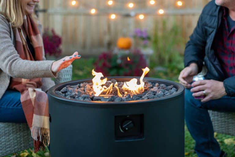 Happy middle age couple sitting by a backyard fire pit in fall, Can You Use Play Sand In A Fire Pit?