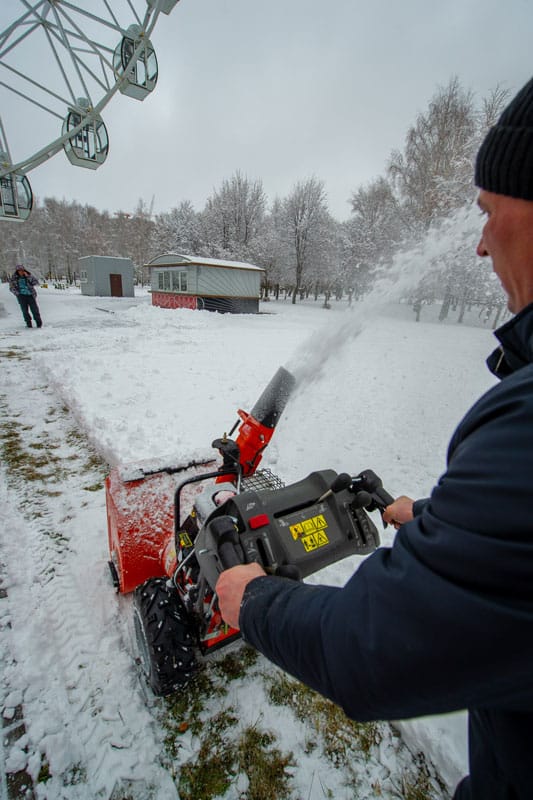 Homeowner clearing the garden with a snow blower