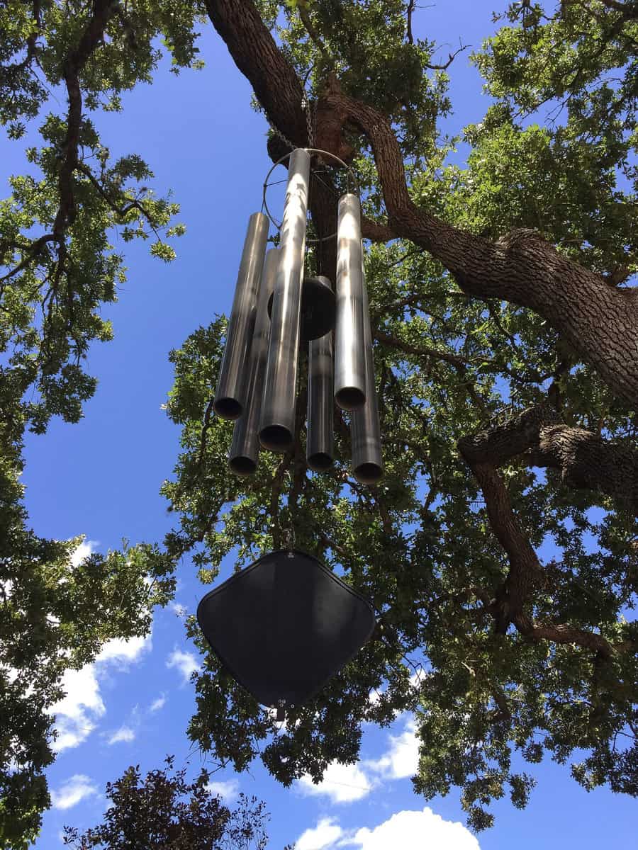 Large wind chimes playing their song as the wind hits them just right in the big tree 