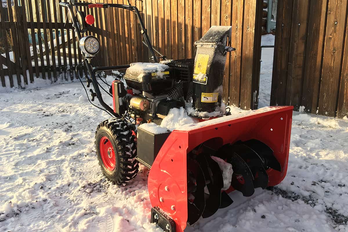 Red snow blower outside home during winter